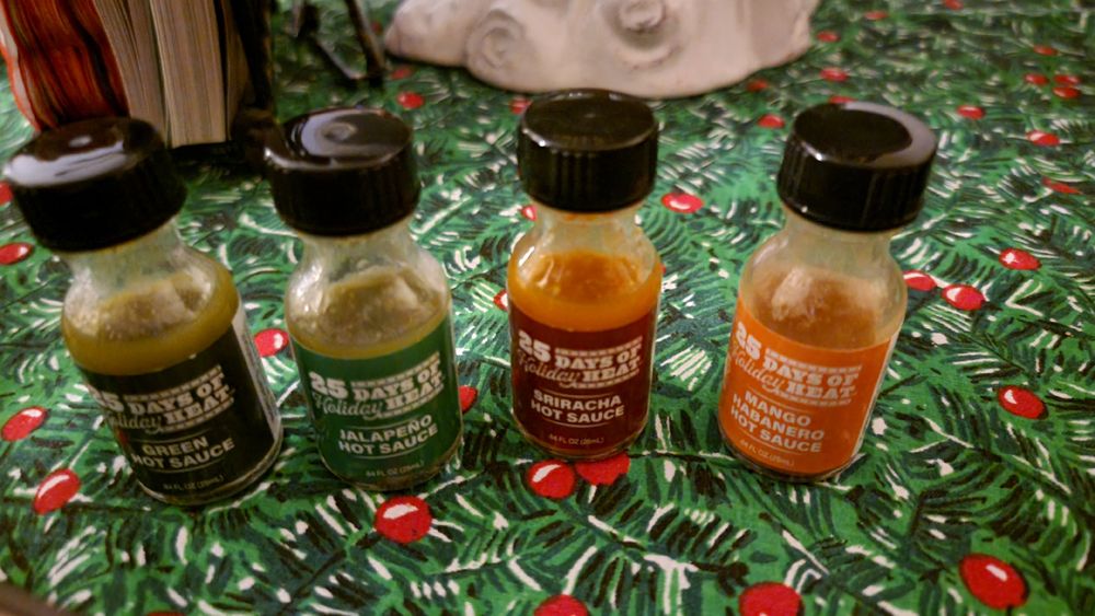 Four miniature bottles of various hotsauce from the Aldi "25 Days of Holiday Heat" advent calendar.