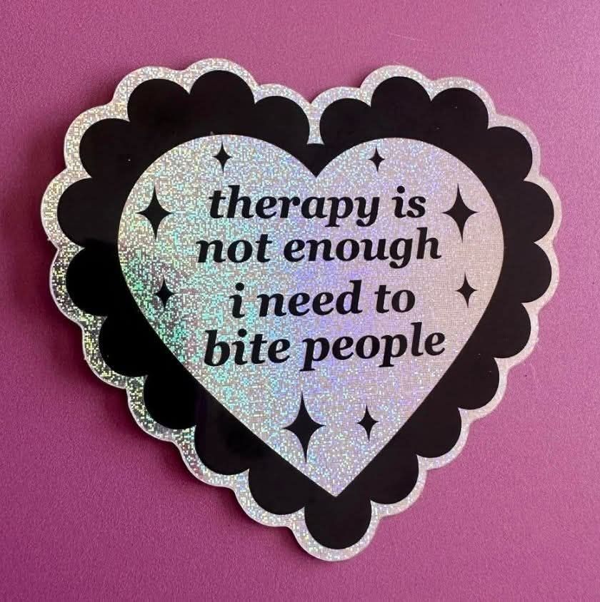 Sparkly silver heart shaped sticker, or perhaps pin, with black decorative border on a pink background. Black shine/star/sparkles of various sizes decorate the heart. The text reads:

"therapy is not enough
i[sic] need to bite people"