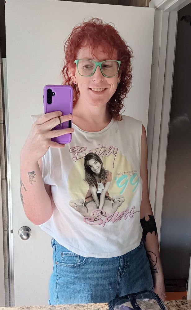 Ripley in a Britney Spears tour tee and blue cutoff shorts