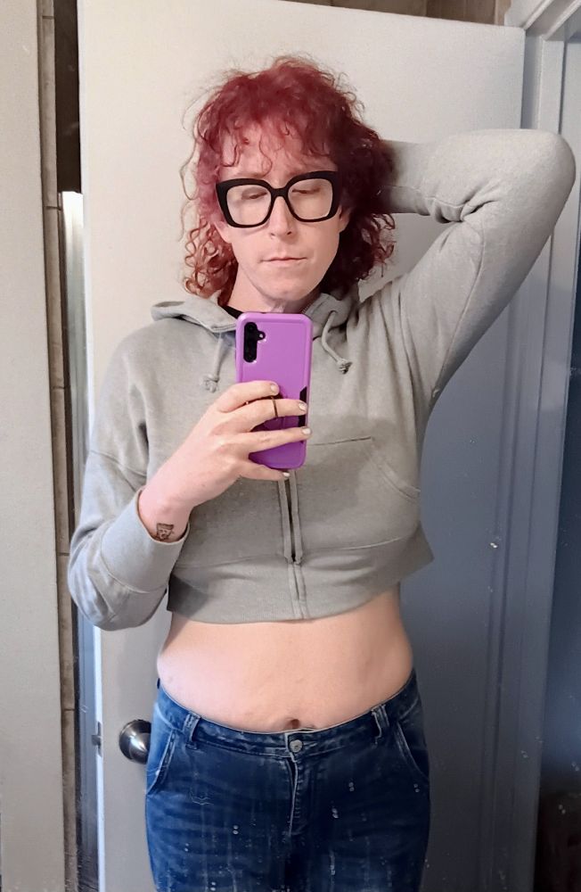 Ripley in a gray cropped hoodie, and blue jeans