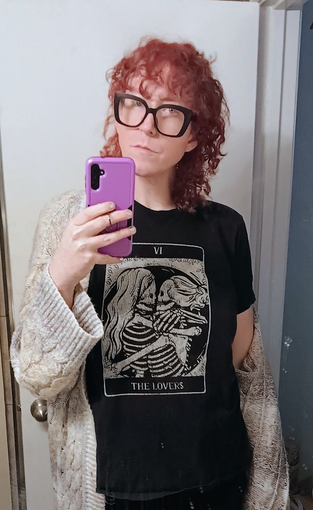Ripley in a black tee with lesbian skeletons kissing for the Lovers Tarot, and a tan cardigan