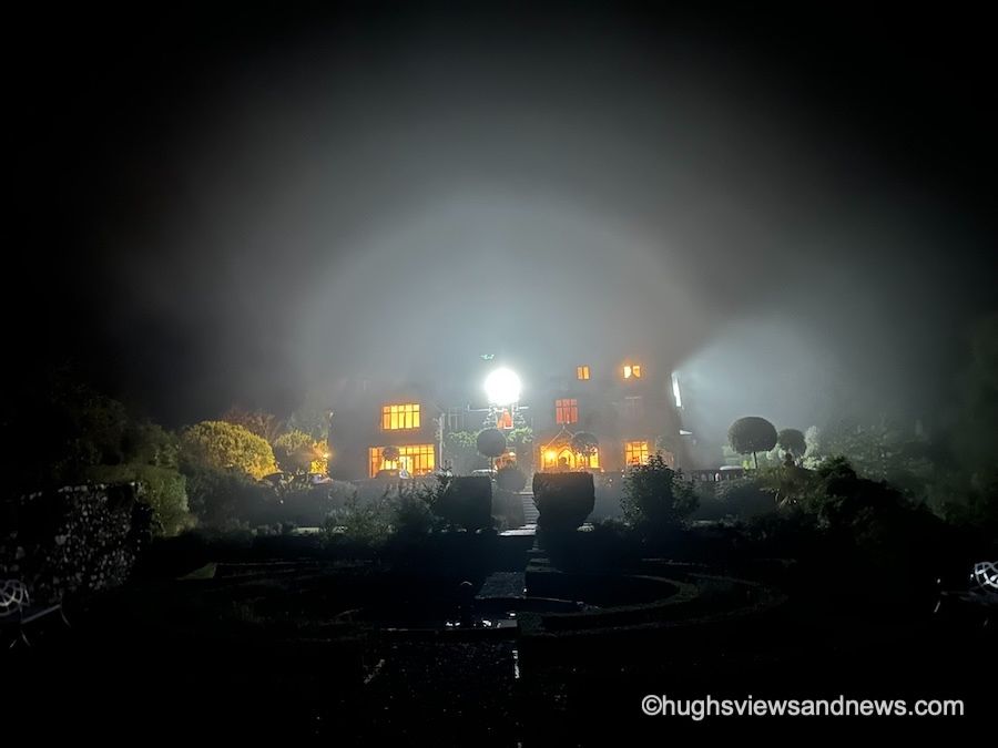A nighttime photo of a hotel illuminated by a security light. Above the hotel is a white halo caused by the light. 