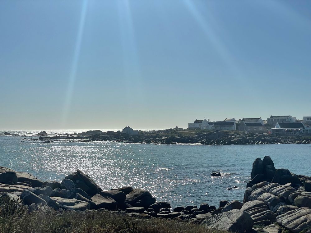 Sunbursts hitting Jacob’s Bay on South Africa’s West Coast; traditional fishing cottages in the background.