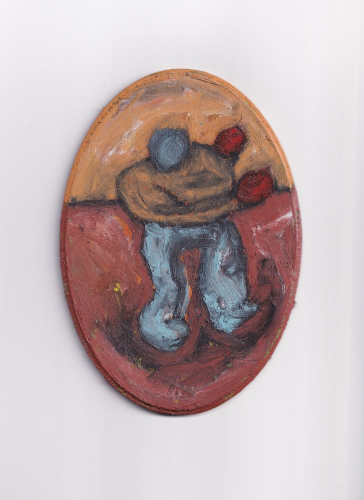 A photo of an oil pigment stick painting on an oval wood panel. The painting shows a human figure with a round, blue head, lacking facial features. They wear a tan long sleeve shirt. Their hands are raised up to the right side of the painting, in a position as if they are ready to fight. On their hands, are two red spheres. Their pants are a light blue/grey. The background consists of a yellow/tan wall similar in color to the figures shirt, and a brown floor/ground. The ground and floor are separated by a black line, that moves behind the center of the figures torso. The painting is done loosely, causing the orange, green, and yellow acrylic underpainting to peek through from behind the oils.