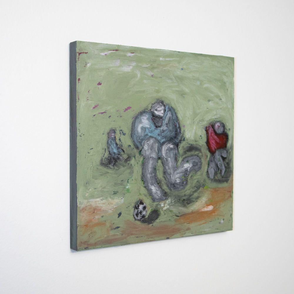 A painting done with oil pigment stick. There are three loosely drawn, human forms. The form in the front/middle is wearing a blue shirt, with grey skin, no facial features, and grey legs with white highlights. The figure has one leg back, ready to kick a black and white soccer ball in front of it. The figure to the right, and slightly behind, is wearing a red shirt, with a grey head, no facial features, and grey legs. The third figure is furthest away, and sits to the furthest left of the painting. it is wearing a blue shirt, and has a grey head. It has very little detail. The soccer ball sits closest to the viewer, on top of a green, brown, and orange ground. The ground fills the entire background, painted loosely, revealing the multicolor acrylic underpainting. The underpainting that peeks through shows colors of red, purple, blue, green and yellow. there are white highlights scattered around the background.