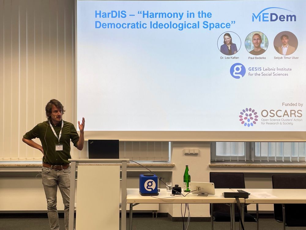 Sebastian Ziaja stands at a podium presenting HarDIS (Harmony in the Democratic Ideological Space) at the 3rd MEDem Conference. A slide behind him shows the HarDIS team (Lea Kaftan, Paul Bederke, Selçuk Timur Uluer) with the logos of MEDem, GESIS Leibniz Institute for the Social Sciences, and OSCARS (the funding initiative).