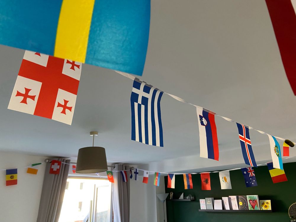 A lounge with bunting across the ceiling, made up of European flags.