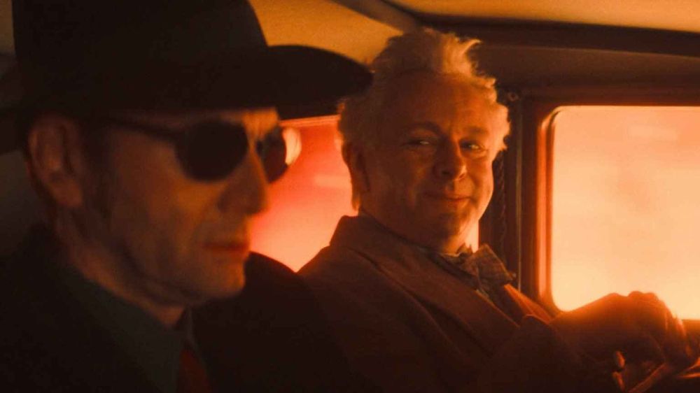 Crowley and Aziraphale are in the Bentley surrounded by flames during the Blitz. Aziraphale is smiling over at Crowley as if he is about to confess his feelings for him