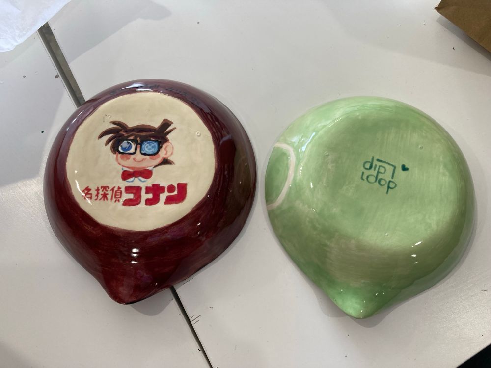 Two painted ceramic trays, one of conan from detective conan with the logo, and the other is green with a signature
