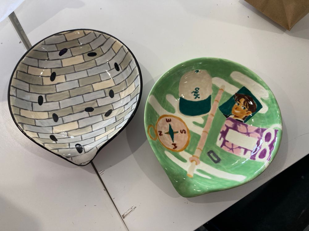 Two painted ceramic trays, one of bricks with footsteps and the other of various items belonging to hattori heiji from detective conan