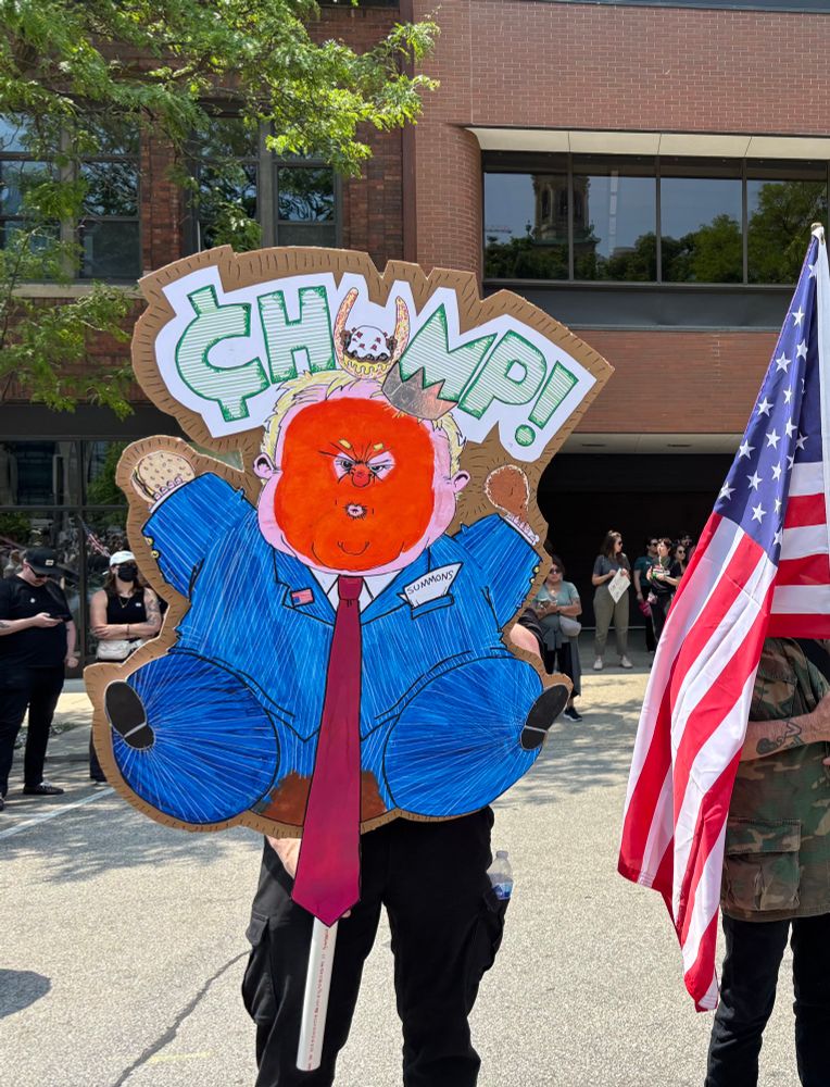 No Kings protest in Milwaukee. Sign is a large hand drawn character Chump