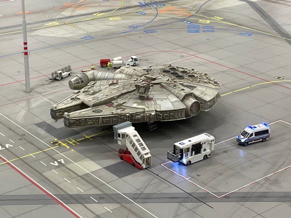 The Millennium Falcon at airport parking position, gangway and other service cars close by - curiously also a police van.