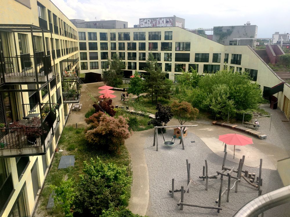 Spielplatz, Bäume und Sträucher im idyllischen Innenhof der Kalkbreite in Zürich.
