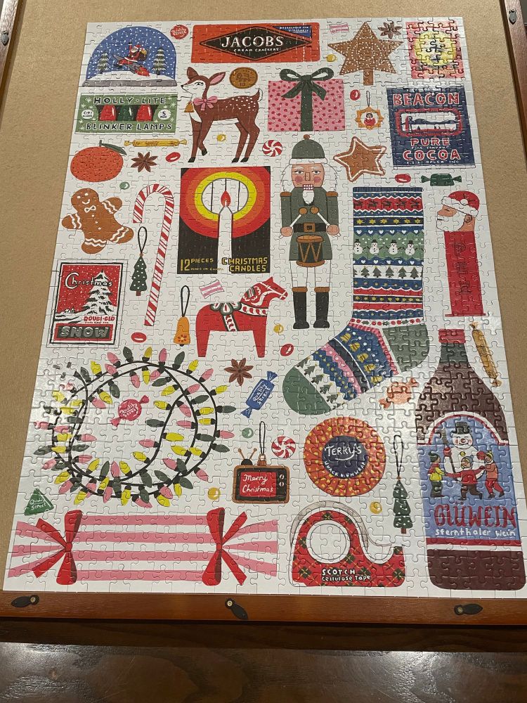 A completed 1000 piece jigsaw puzzle on an easel board - the puzzle is Christmas themed and features various holiday items such as a string of Christmas lights, a stocking, a candy cane, etc.