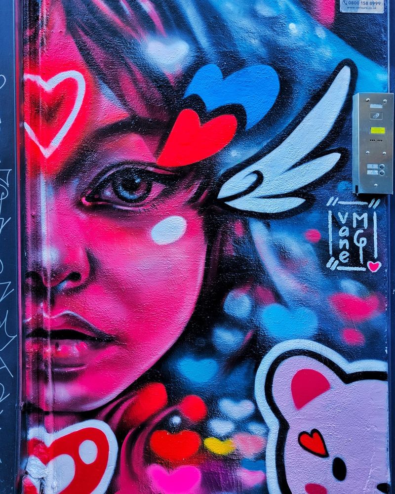 A streetart photo of a half profile women's face in bright neon colours surrounded by hearts