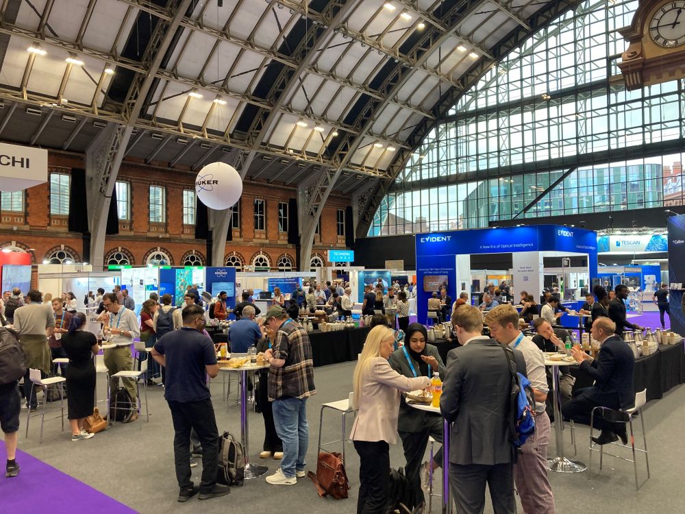 A busy exhibition hall at mmc2025. Delegates enjoy their lunch, with the domed roof of Manchester Central featuring prominently in the top half of the image.
