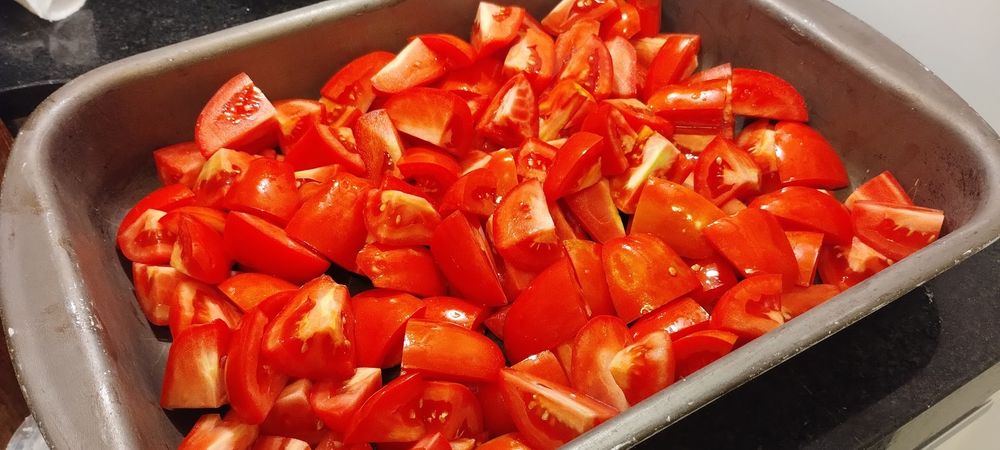 uma assadeira com tomates cortados grosseiramente espalhados nela toda