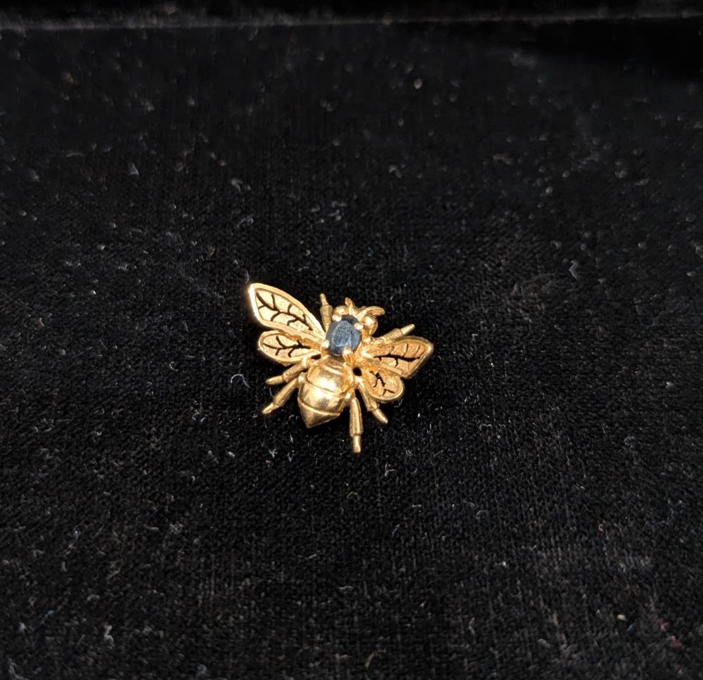 Petite abeille en or (~1 cm), les ailes déployées aux nervures ajourées et un petit saphir sur le dos 