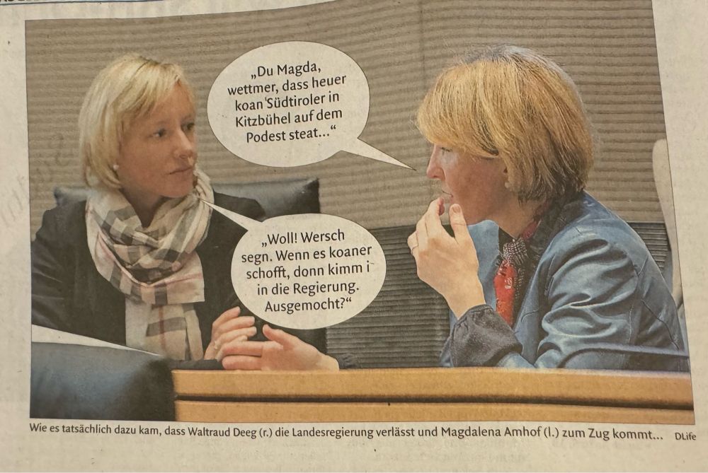 Foto von Magdalena Amhof und Waltraud Deeg, die nebeneinander im Landtag sitzen. Dazu zwei Sprechblasen:

Deeg: „„Du Magda, wettmer, dass heuer koan Südtiroler in Kitzbühel auf dem Podest steat...“
Amhof: „Woll! Wersch segn. Wenn es koaner schofft, donn kimmi in die Regierung. Ausgemocht?“