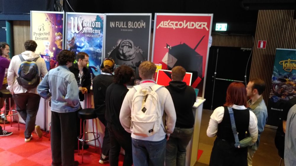 A crowd of players surround the two obleak games booths: In Full Bloom on the left and ABSCONDER on the right.