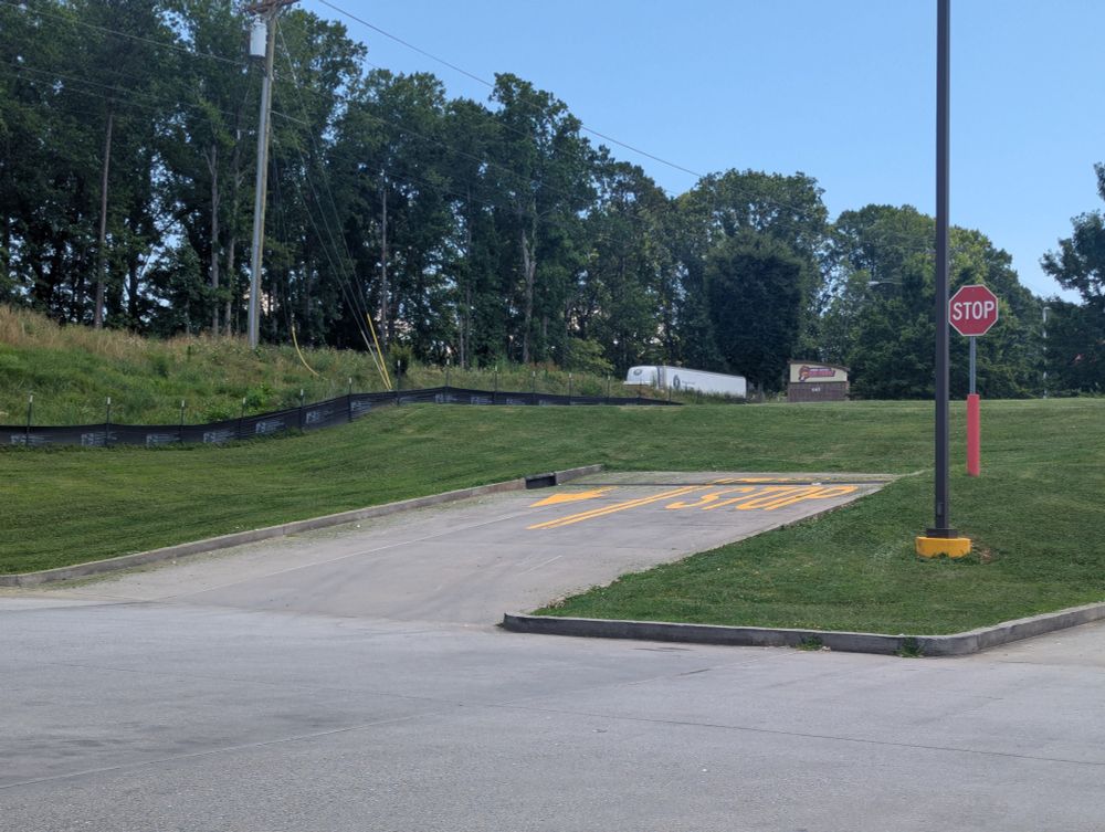 A sloped entrance/exit, complete with directional markings and a stop sign, leading out of a parking lot that terminates abruptly on a grassy knoll. The adjoining lot has a car wash there but they just never connected the two lots for some reason.