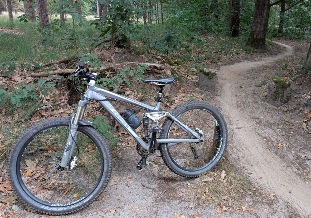 My 15 years old Trek Fuel Ex mountainbike next to a singletrack in the woods.