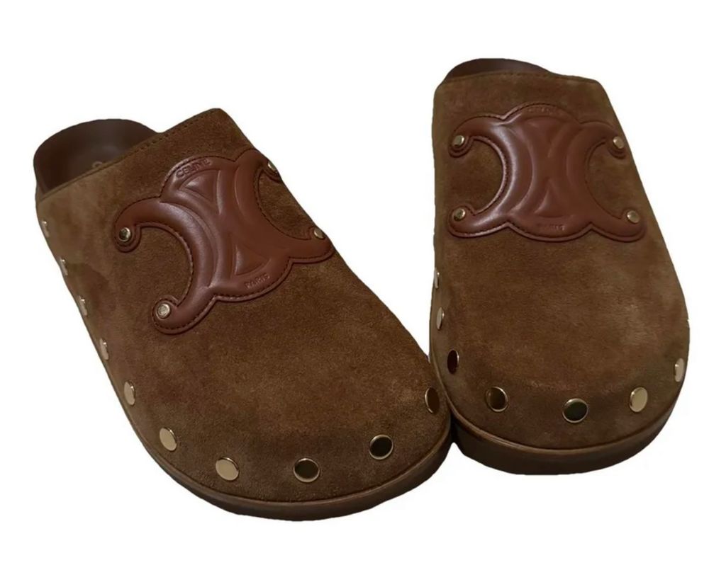 Paire de chaussures de la marque Céline en forme de sabots plats en nubuck marron clair avec des rivets dorés sur le bord et le logo de la marque en cuir marron.
