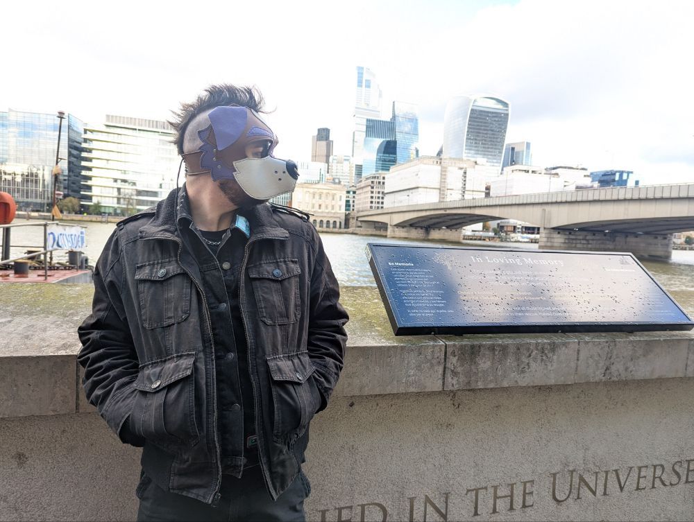 delete is standing "casually" in front of one of the million bridges in london. there is a bautiful and varied skyline behind him, and his mohawk is "candidly" framed against the sky. here he is wrapped up warm, in layers and layers of black denim