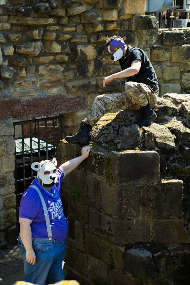 sisco standing amidst the castle ruins with a world-weary stare at the camera. off to the side I can be seen climbing over the rocks and having a blast