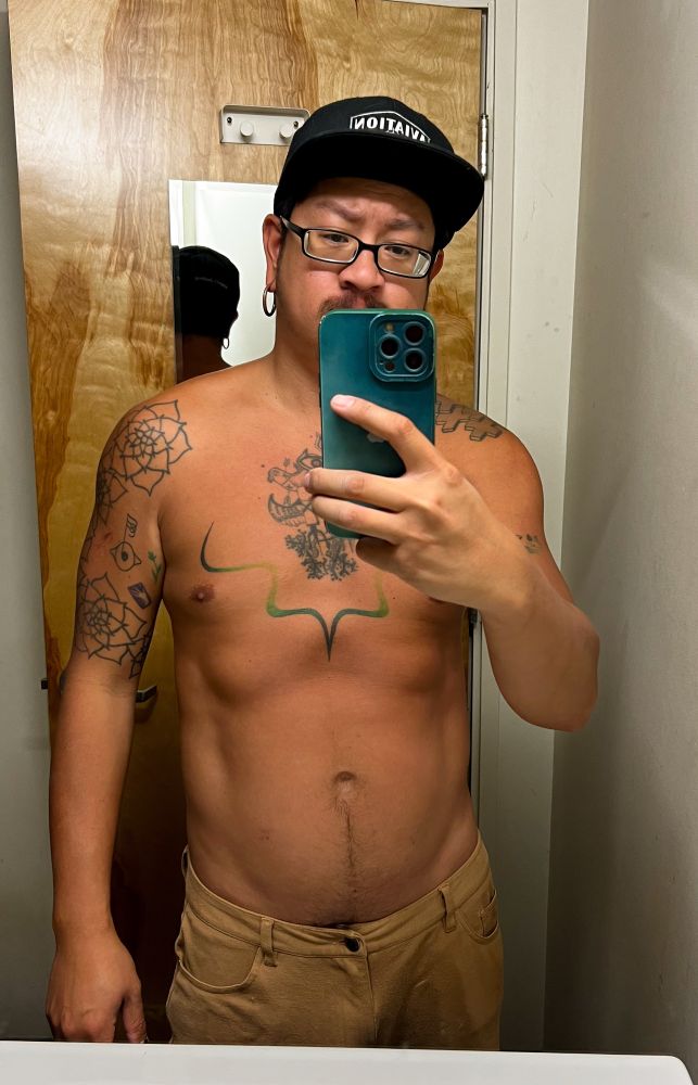 Mirror selfie of tattooed guy in shorts and hat