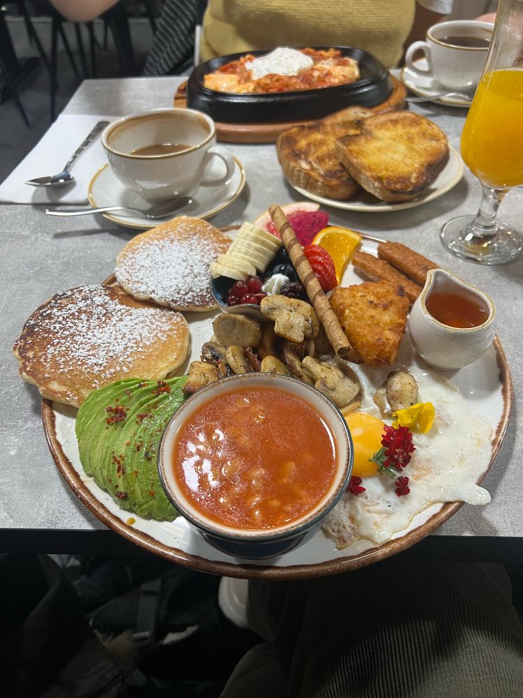 A large breakfast completely with pancakes, mushrooms, beans, avocado, hash browns, egg and more 