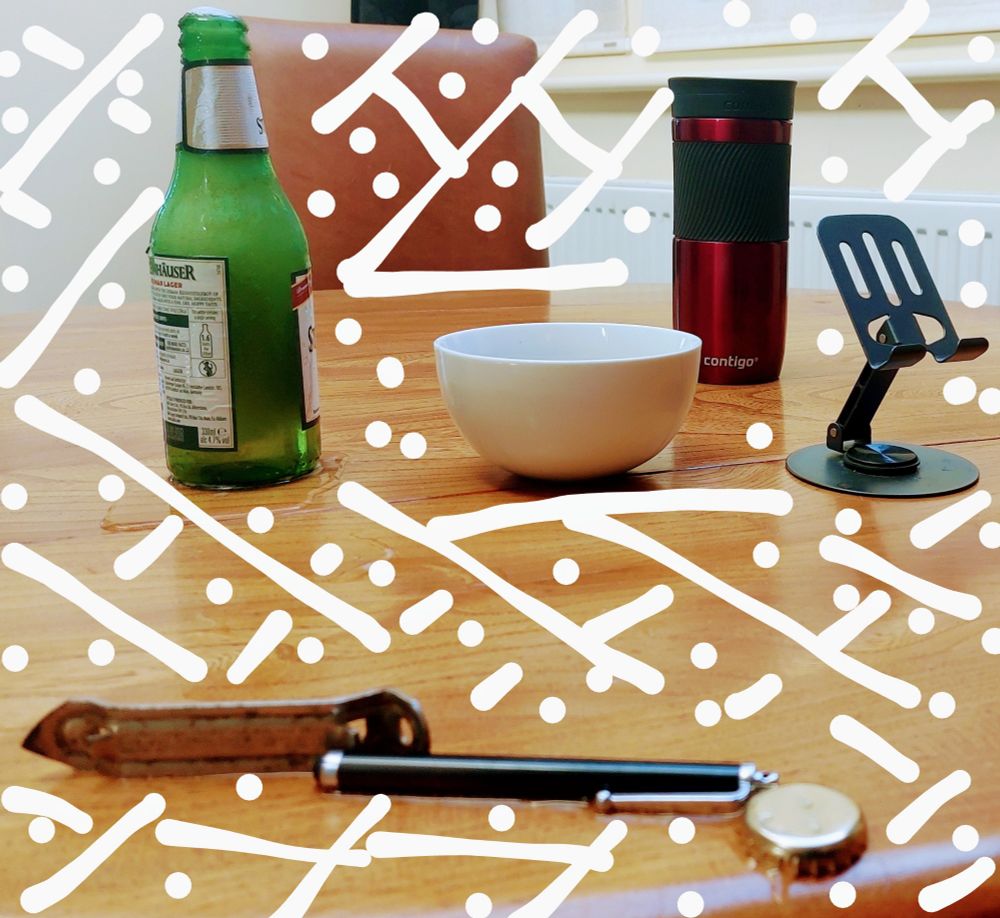 .. objects on a wood table top .. green beer bottle, bowl, red flask, smart phone stand .. below in a line to direct the beer overflow .. the beer top, pen, bottle opener .. a lattice of white lines suggest a web of some sort .. take it as it resonates ..