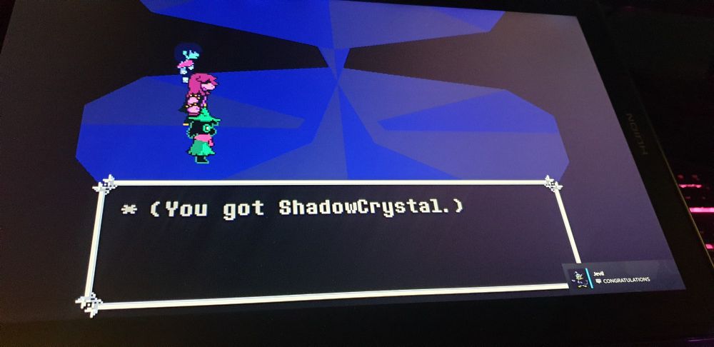 A picture of my tablet screen showing I defeated Jevil in Deltarune. There is a Steam chat popup of Jevil congratulating me ( It's actually a friend of mine who changed their profile ).