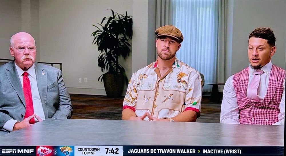 Andy Reid in a suit, Travis Kelce in casual shirt and cap, Patrick Mahomes in a pink vest and tie