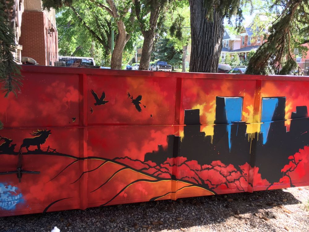 Spray paint and acrylic paint mural depicting a cityscape at sunset.