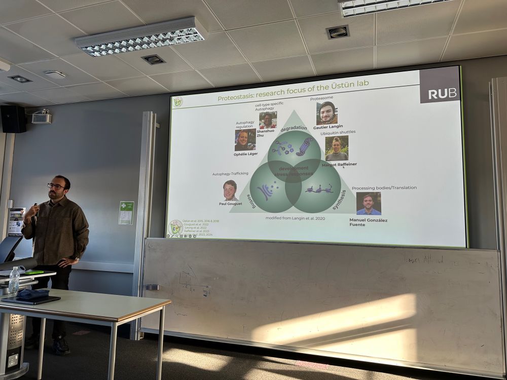 Suayb Üstün standing in a lecture theatre presenting a PowerPoint overview of the research interests of his group 