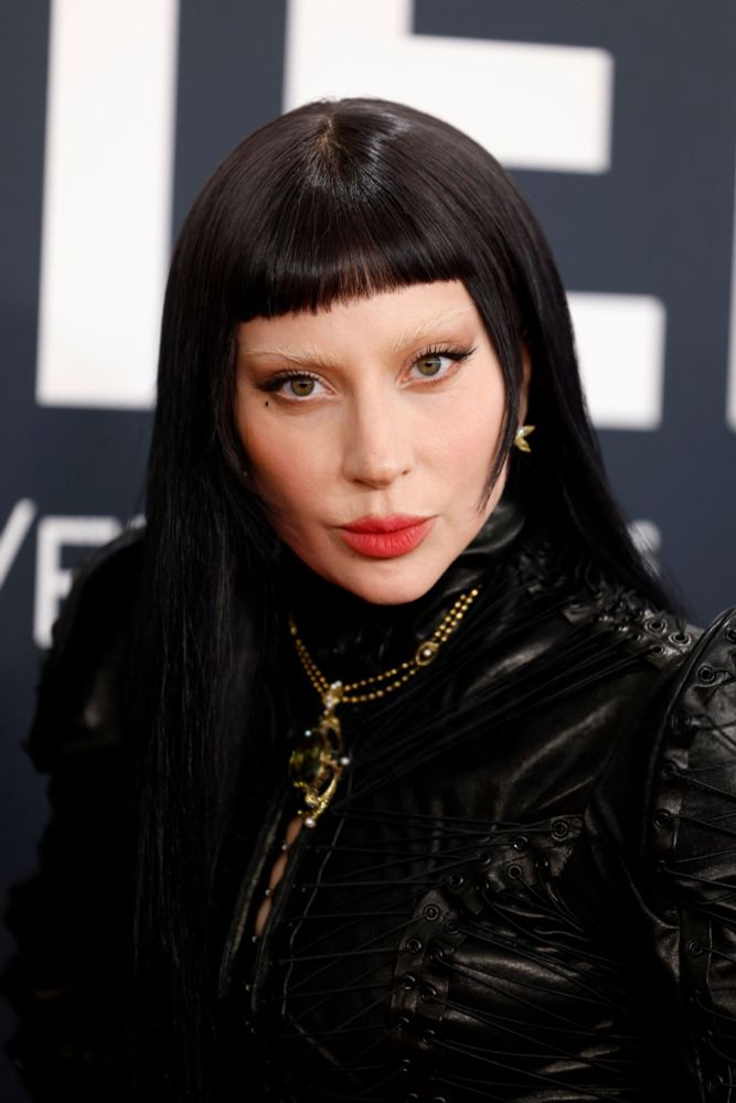 lady gaga de peruca preta e vestido preto olhando pra câmera 