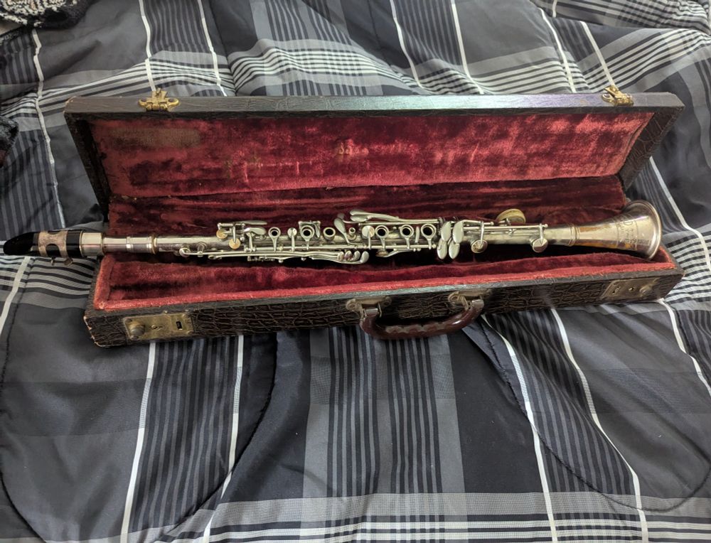 A brass clarinet, lying in its case