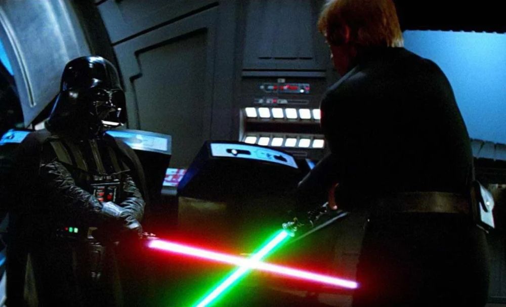 Darth Vader, holding a red lightsaber, battles Luke Skywalker, holding a green lightsaber.