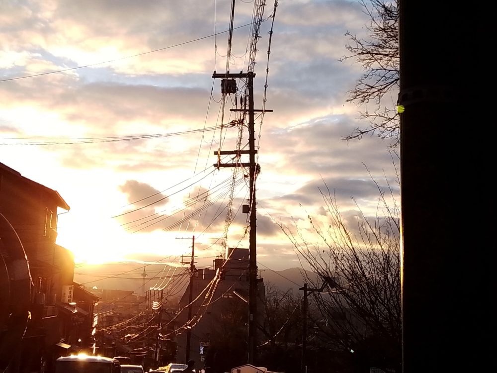 Sunset viewed viewed a hill in Kyoto. Traditional and modern buildings can be seen along with electricity cables.