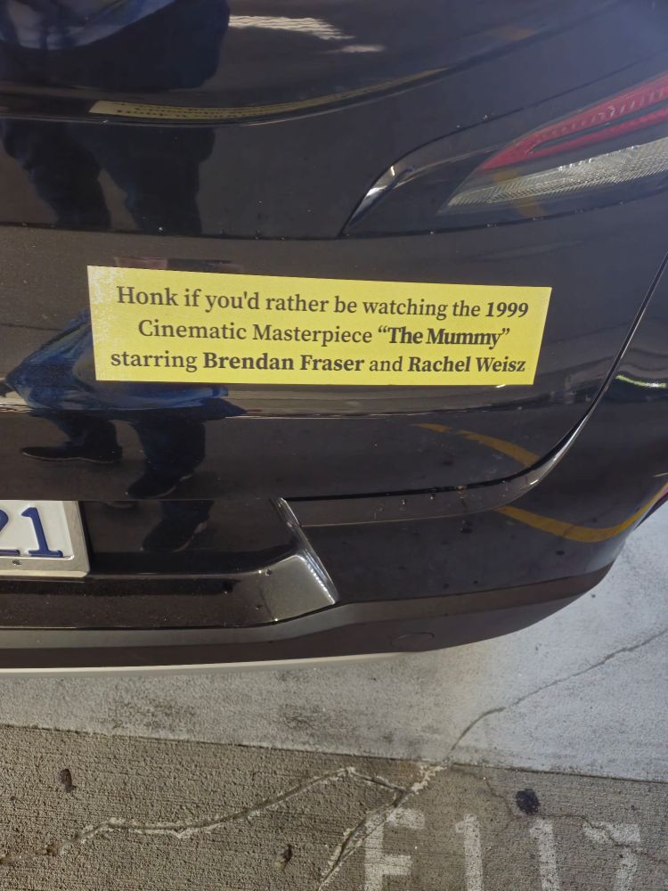 bumper sticker reading "honk if you'd rather be watching the 1999 cinematic masterpiece The Mummy starring Brandan Fraudster and Rachel Weisz"