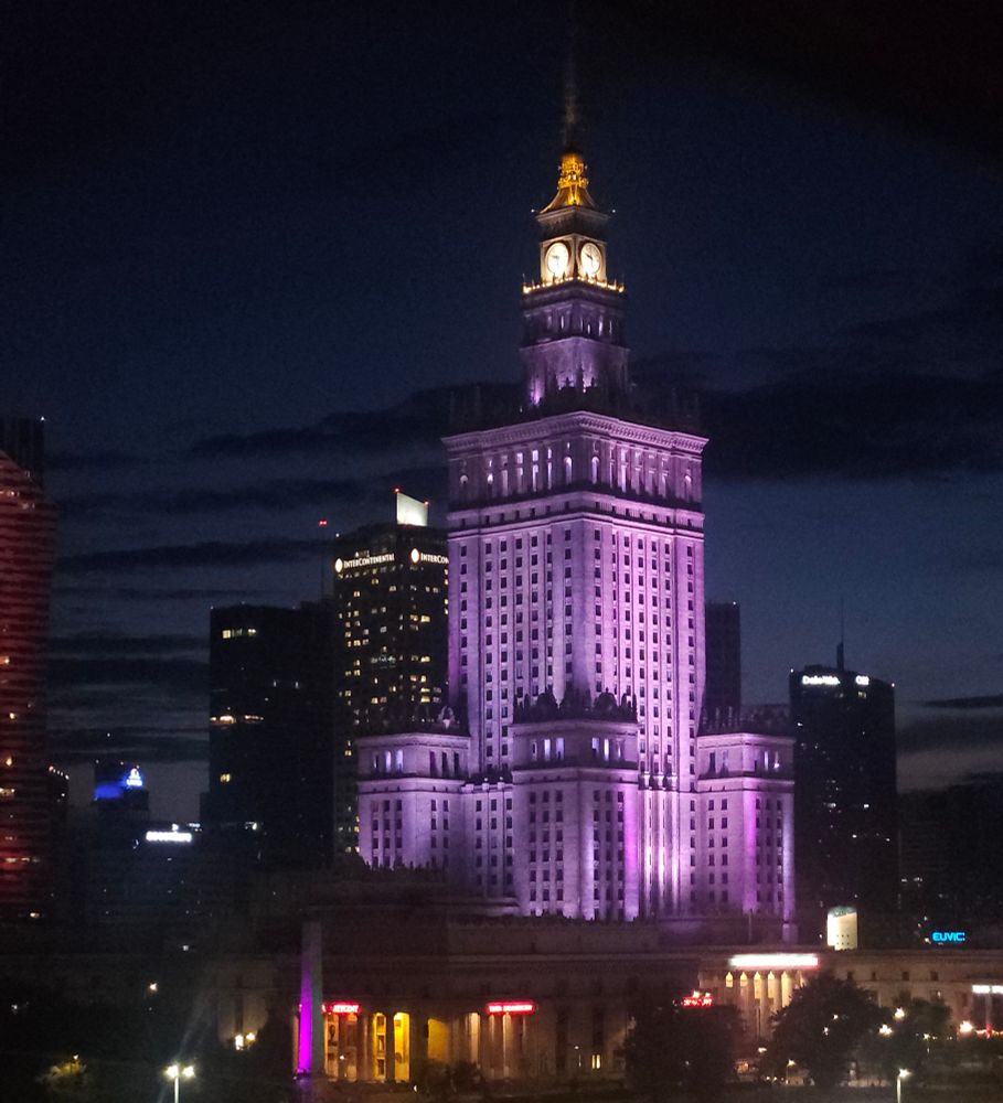 Der Kulturpslast in Warschau bei Nacht mit violetter Beleuchtung.