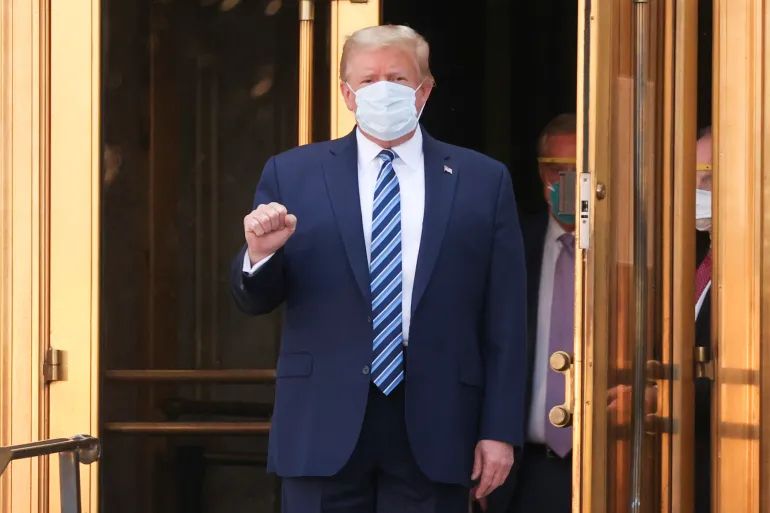 Photo of Trump in surgical mask with a partially raised fist. Taken in 2020 after his hospitalization for COVID.