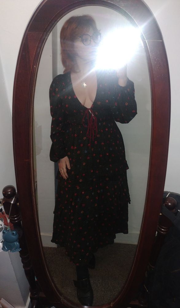 mirror selfie with flash reflecting off mirror partially obscuring woman's face shoulder length red hair glasses deep v long sleeve maxi dress black heeled shoes