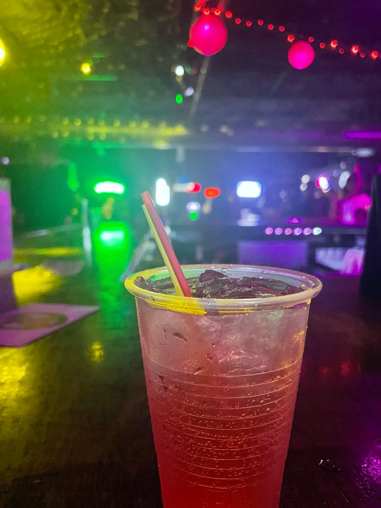 A vodka cran photographed in a dim bar with neon lights scattered around