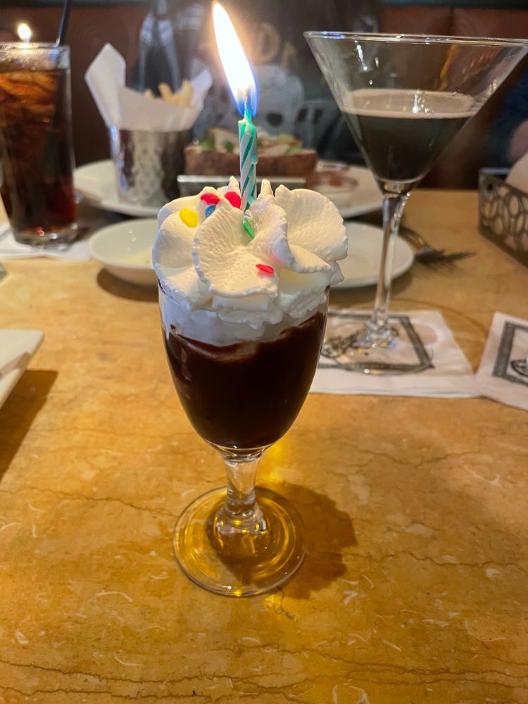a small hot fudge sundae with whipped cream and a lit candle