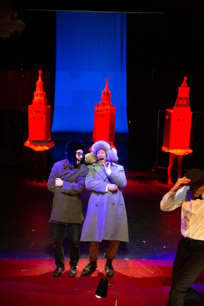 Kon (Eric Tabach) and his friend Anton (Elan Zafir), wear big furry Russian hats, gossip and laugh in Red Square, which is represented by  three actors wearing huge models of Kremlin towers 