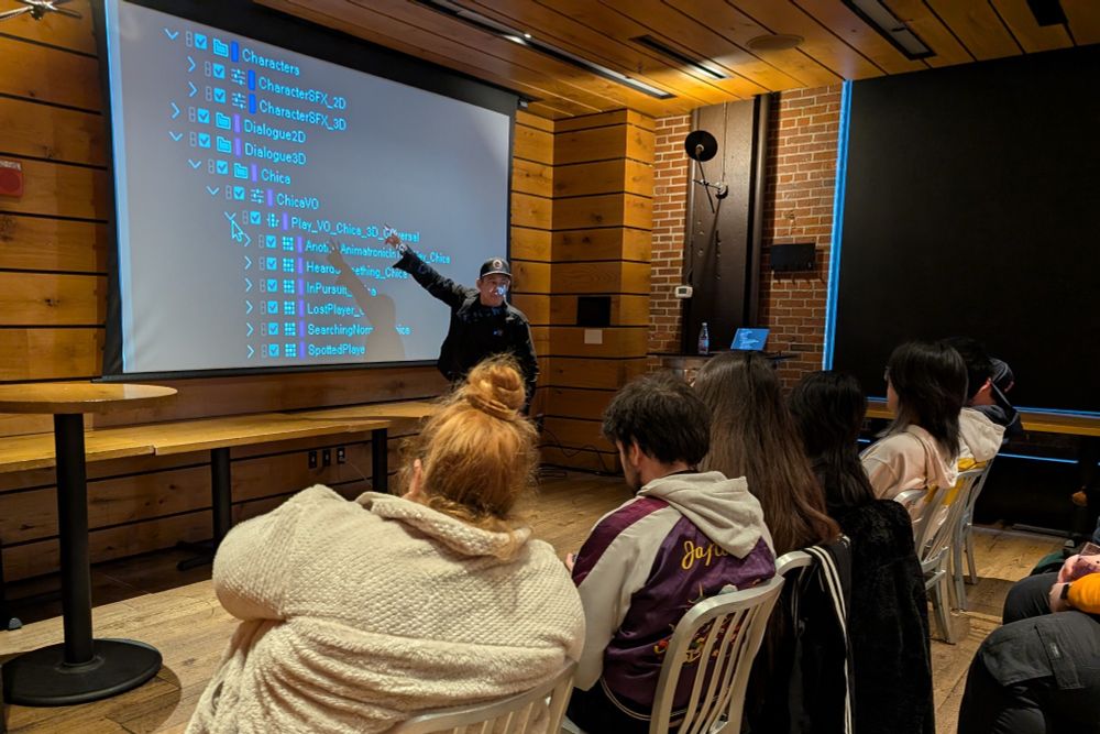 The Game Audio Hang at BGW. Duncan Watt is gesturing at his work in Wwise on a projector to a seated audience.