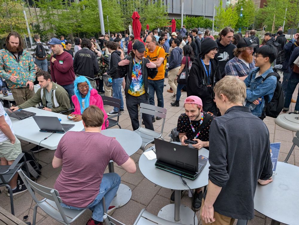 A crowd of people chatting and playing game demos outside.