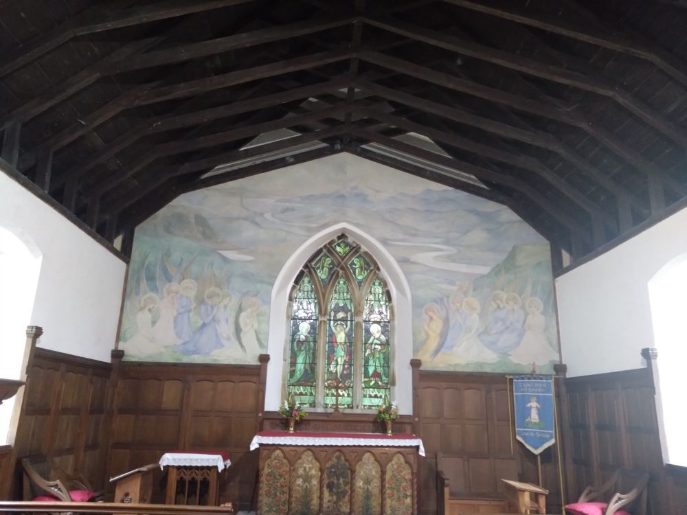 Altar in a little wood panelled chapel, with a beautiful painted mural of countryside hills and angels behind 